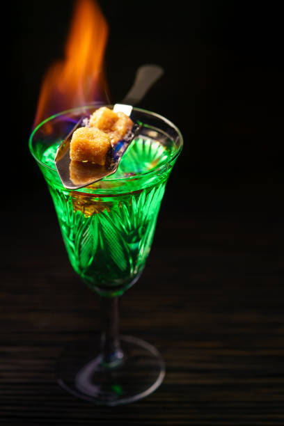 istock Burning absinthe  in glass and spoon with  brown sugar cubes on dark table background 1423421057