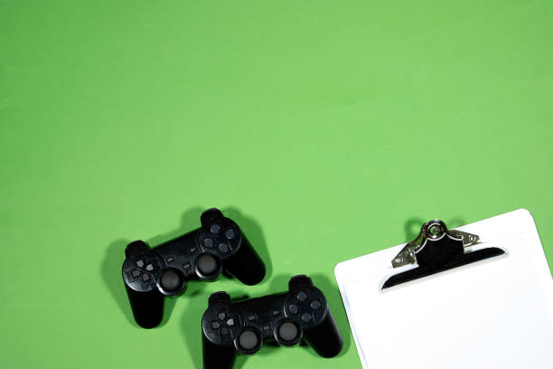 istock black joysticks, game controller with with Classic metal clipboard blank white paper  on  green background 1423421075
