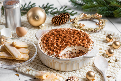 Festive Christmas Dessert Tiramisu sponge cake in bright rustic kitchen with golden Christmas Ornaments