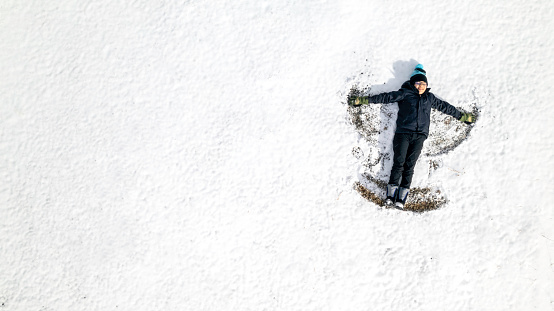 High quality stock photos of a boy making a snow angel from above.