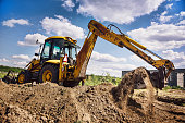 Excavator at house construction site - digging foundations for modern house