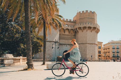 Woman ridding bicycle by Torres de Serranos city gate of Valencia Spain