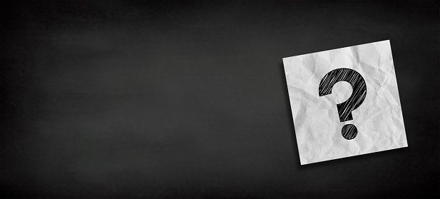 Crumpled note paper with question mark on black background