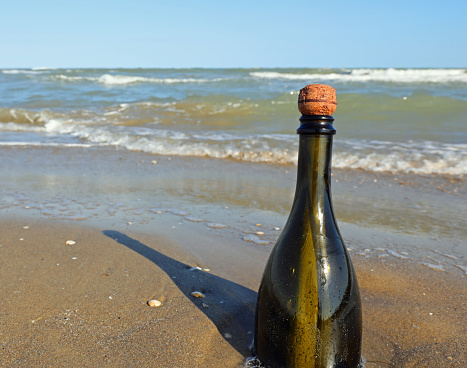 beached green glass bottle with a message inside on the foreshore near the beach