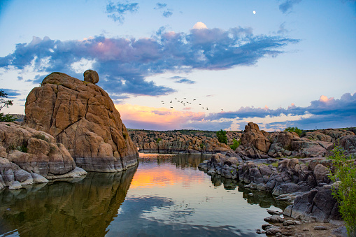 Watson Lake at sunset with a small flock of birds flying through the shot.