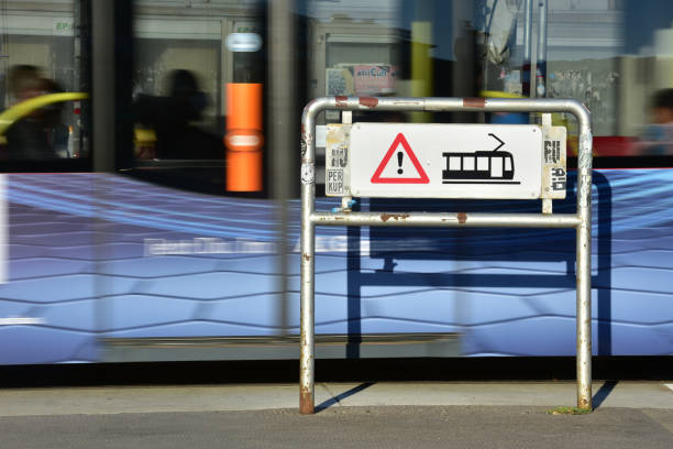 Pedestrian crossing with a warning sign at a tram stop near the Westbahnhof in Vienna with a blurred tram in the background
