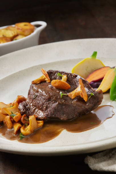 Red Wine Braised Beef Cheek Red Wine Braised Beef Cheek with Chanterelles, Garden Vegetables and Madeira Jus madeira sauce stock pictures, royalty-free photos & images