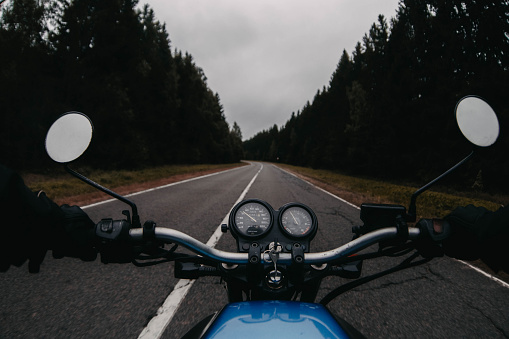 Motorcycle adventure, ride on asphalt forest road in autumn. First-person view.