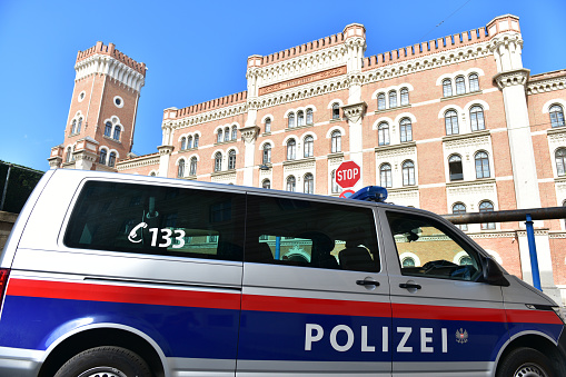 Police car in front of the well-known Rossauer Kaserne in Vienna, headquarters of the Austrian Federal Ministry of Defense, in the summer with blue sky