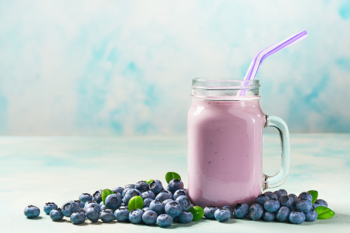 Homemade smoothie with fresh blueberry on a turquoise wooden background