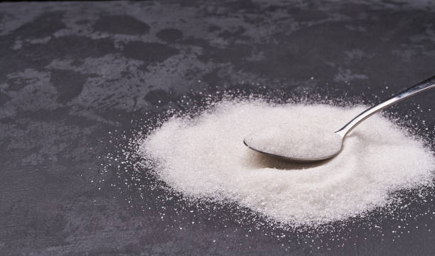 istock Sugar powder in a metal spoon on a black background. 1423442503