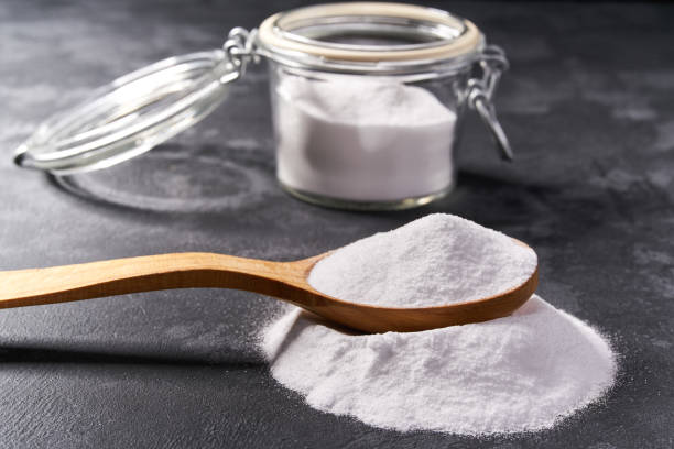 istock Baking soda  in a wooden spoon on a black background . 1423442529