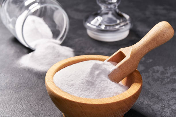 istock Wooden bowl with sodium bicarbonate close-up  on a black background , 1423442547