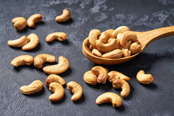 istock cashew nuts  in wooden spoon  on black table,close-up 1423445018