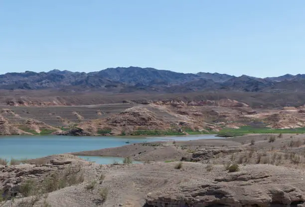 Viewpoint from interior rocky shoreline within Lake Mead, water receding due to severe drought climate change.