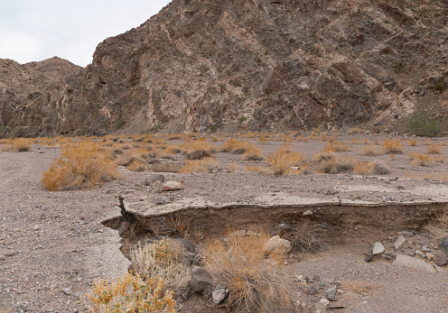 Heat cracked back road trail crumbled and collapsed in disrepair during summer within Lake Mead recreation area.