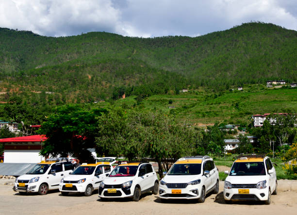 Khuruthang, Punakha District, Bhutan: taxis to Timphu wait for passengers on the main street - mountains in the background - Bhutanese taxis. There is no Uber in Bhutan.