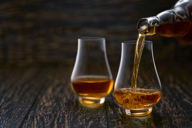 istock Man pouring whiskey in glasses on rustic wooden table selective focus. 1423448837
