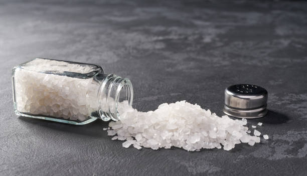 istock Pile of salt and salt shaker on black stone background. Horizontal composition. 1423448870