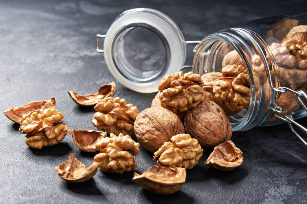 istock Walnut in an open glass jar on black table, close-up. 1423448918