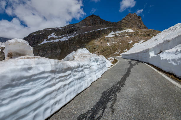 альпийская горная дорога между снегом весной, альпы гран-парадизо, италия - melting spring snow trentino alto adige стоковые фото и изображения