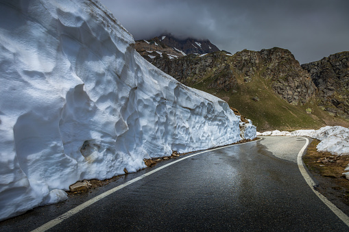 Alpine mountain road between snow at springtime, Gran Paradiso Alps, Italy, near border with France