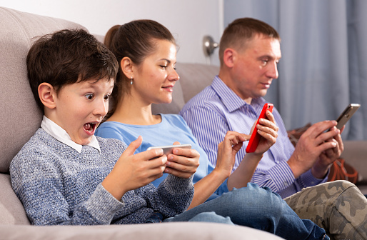 Modern family sitting with smartphones in home interior