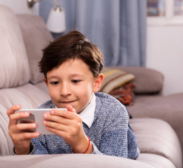 istock Preteen boy resting with smartphone on sofa at home 1423458326