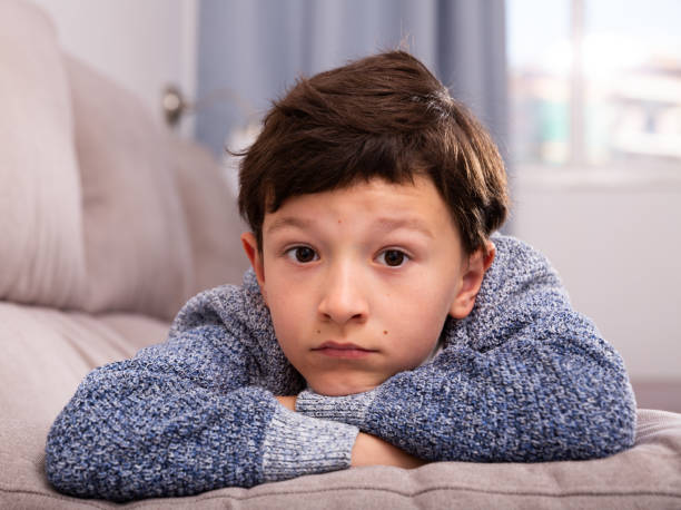 istock Unhappy schoolboy sitting at sofa and thoughtful about  trouble 1423458352