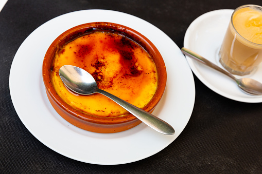 Delicious traditional Spanish dessert - Crema catalana served with spoon in clay bowl