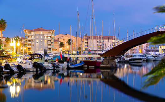 Evening view of coastal area of Frejus with illuminated quays and port