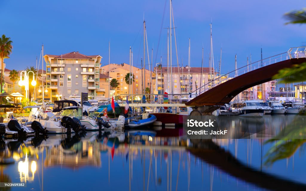 Evening view of coastal area of Frejus with illuminated quays and port Picturesque evening view of coastal area of Frejus with comfortable residential buildings along illuminated quays and port for pleasure boats in summer, France Architecture Stock Photo