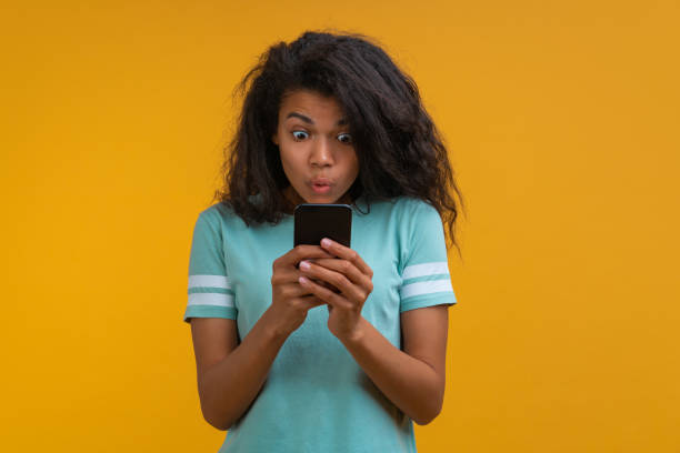 istock Studio portrait of a girl reading message on her smartphone with surprised face expression 1423459561