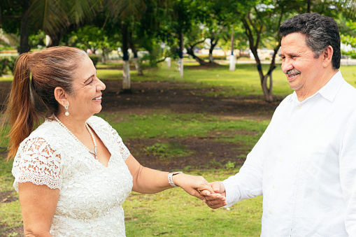 Hispanic bride and groom holding hands at a wedding