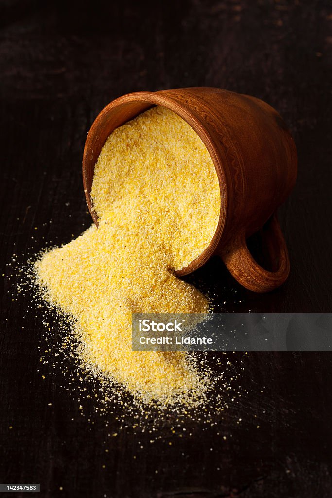 Cornmeal. Polenta spilling onto an old wooden table. Backgrounds Stock Photo