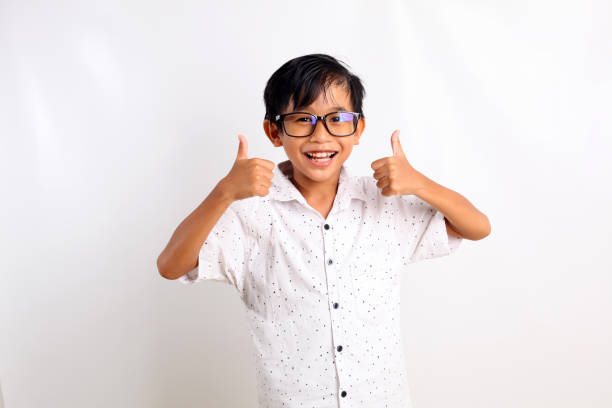 istock Cheerful asian little boy standing while showing thumbs up. Isolated on white background 1423478048