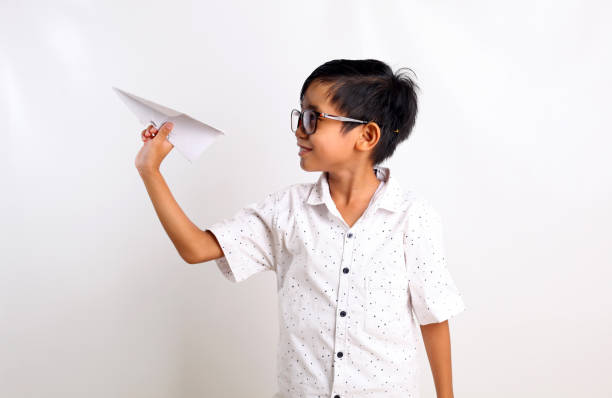 istock Smart asian boy holding paper airplane isolated on white background. Be free and creative concept 1423478663