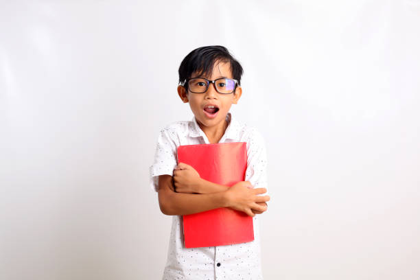 istock Surprised asian schoolboy standing while carrying a book. Isolated on white background 1423478766