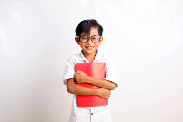 istock Happy asian schoolboy standing while carrying a book. Isolated on white background 1423478906