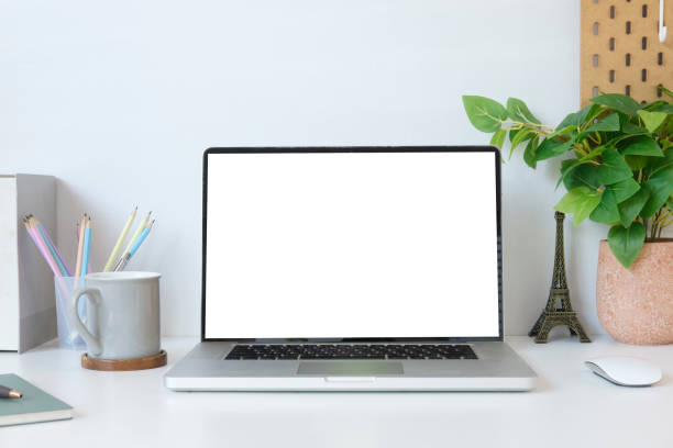 istock Contemporary workplace with laptop computer, picture frame, stationery and flower pot. Blank screen for your advertise text. 1423481140