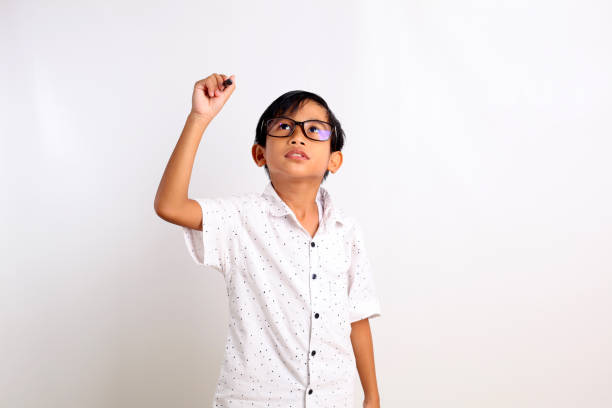 istock Smart asian schoolboy standing while writing something. Isolated on white background with copyspace 1423481304