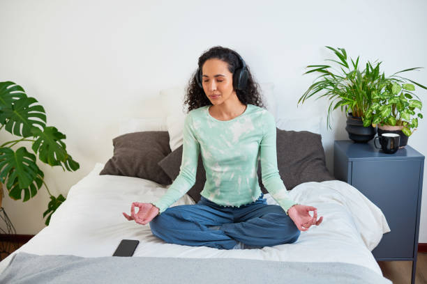 istock A young multi-ethnic woman sits on her bed meditating with mindfulness app 1423481453