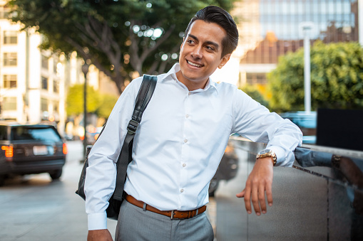 Portrait of a aspiring young adult businessman leaning on the fence in a corporate area in Los Angeles.