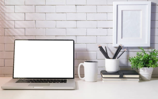 istock Laptop with blank screen, coffee cup, notebook and houseplant on white table in bright modern workplace. 1423484057