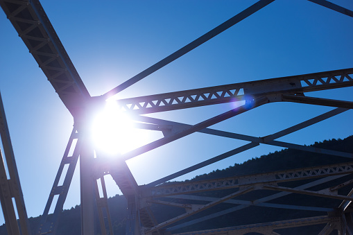 Taos, NM: Sun Over Taos Junction Bridge, Looking Up. Blue sky background. Copy space available.