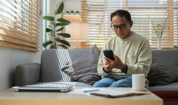 istock Happy senior man resting on couch and using smart phone. Older people and gadgets. 1423487062