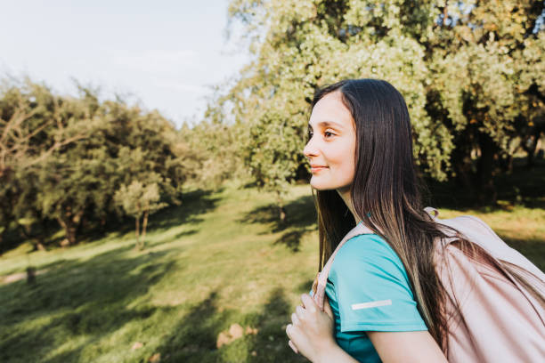 istock Side view young student girl using pink backpack looking at the horizon from the hill. Self-confidence. 1423489482