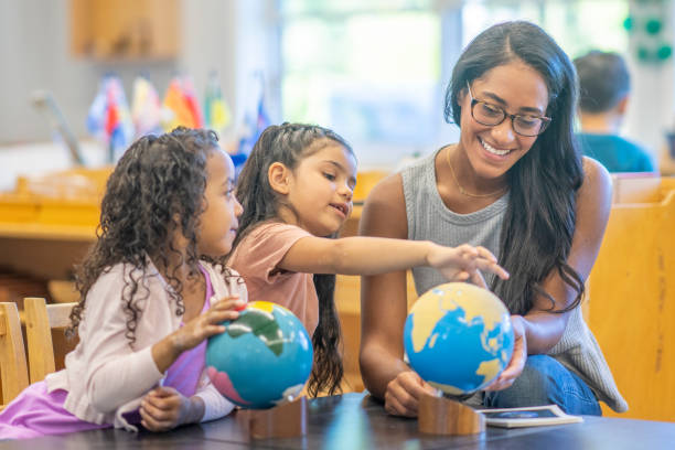 istock Montessori Teacher Looking at a Globe with Students 1423490811