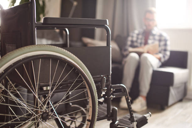 istock Man reading book, wheelchair in front of him 1423512897