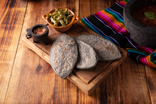 Tlacoyos and Nopales. Mexican pre hispanic dish made of blue corn flour patty filled with refried beans. Popular street food in Mexico
